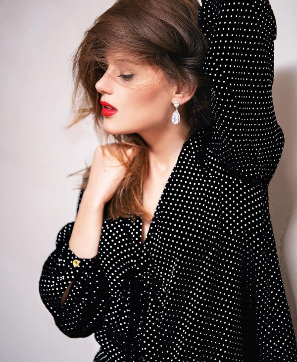 Mujer con vestido negro de puntos blancos, representando la moda sostenible y elegante con un estilo sofisticado y atemporal.